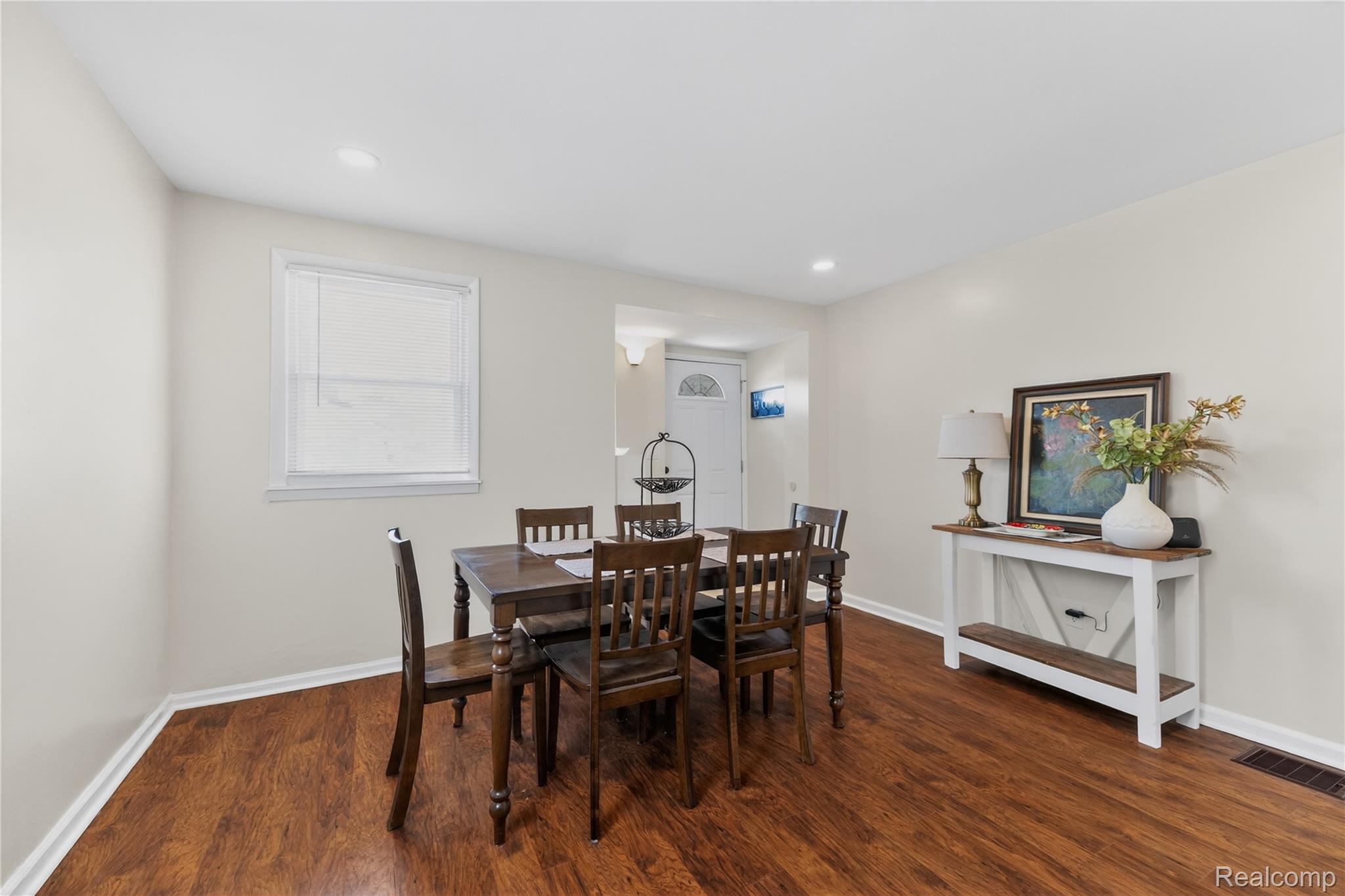 826 Goddard Road Wyandotte, MI 48192 - Photo 4 of 39 Bright dining area featuring warm wood-finish flooring, a wood dining table with four chairs, recessed ceiling lighting, and a large window with white trim