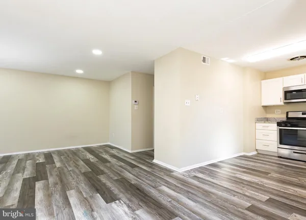 a view of kitchen and empty room with wooden floor