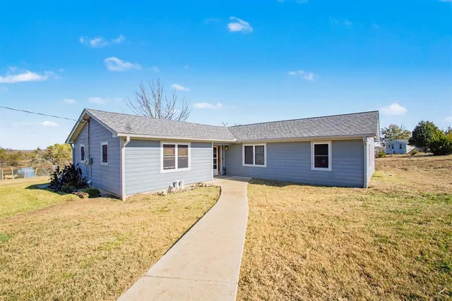 a front view of house with yard and trees in the background