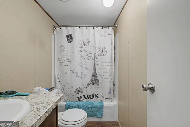 a bathroom with a granite countertop sink toilet and shower