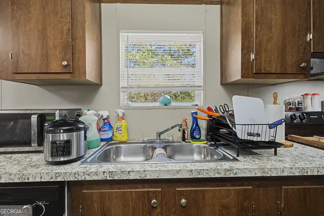 a kitchen with granite countertop a sink a stove and a wooden cabinets