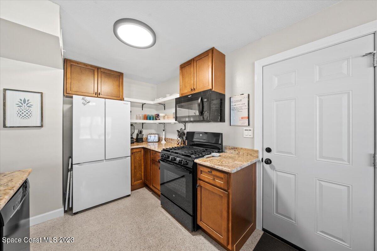 550 Capri Road Cocoa Beach, FL 32931 - Photo 11 of 36 a kitchen with stainless steel appliances granite countertop a refrigerator a stove a sink and a microwave