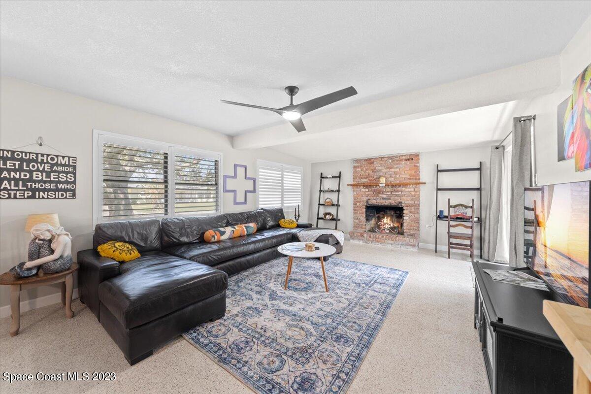 550 Capri Road Cocoa Beach, FL 32931 - Photo 7 of 36 a living room with furniture a fireplace a rug and a large window