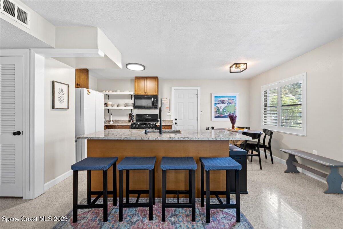 550 Capri Road Cocoa Beach, FL 32931 - Photo 9 of 36 a kitchen with stainless steel appliances dining table chairs and granite counter tops