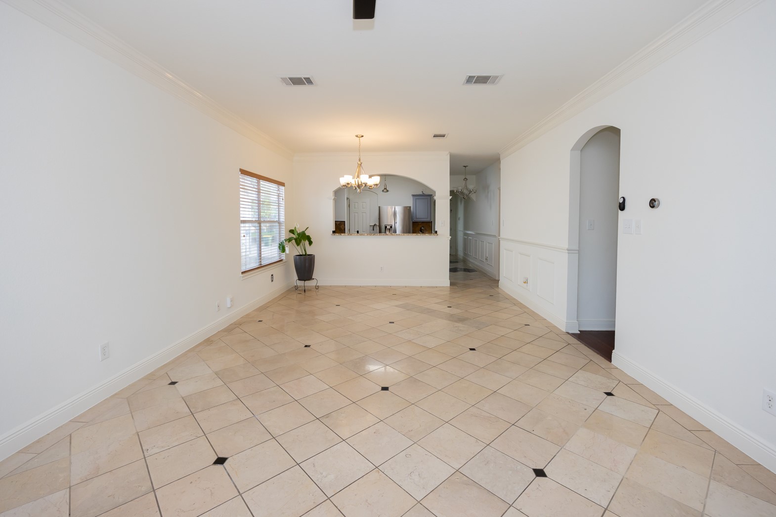 11500 Dimmit Street Manor, TX 78653 - Photo 7 of 14 Spacious interior featuring large square tile flooring with contrasting accent tiles, white baseboards, and crown molding