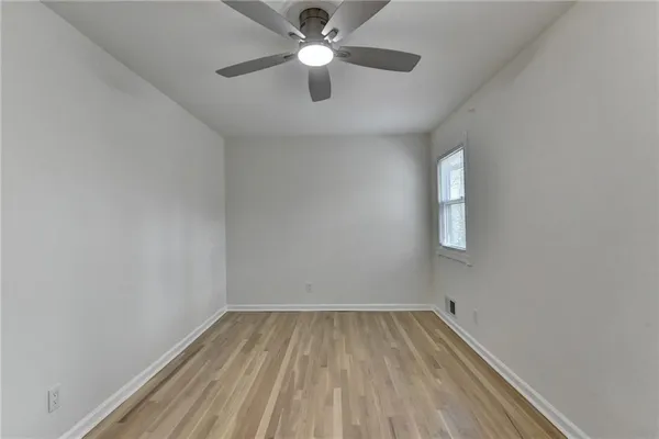an empty room with wooden floor fan and windows