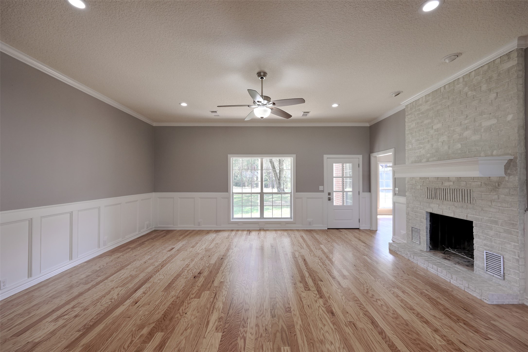 2 Highland Drive Huntsville, TX 77320 - Photo 12 of 50 an empty room with wooden floor fireplace and windows