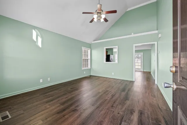 a view of an empty room with wooden floor and a window