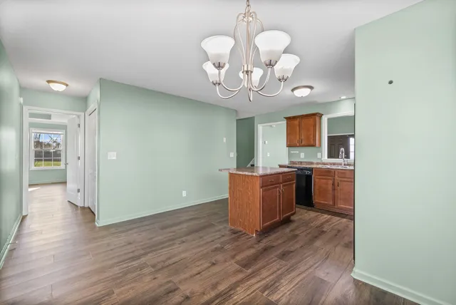 a large kitchen with a chandelier stainless steel appliances and wooden floor