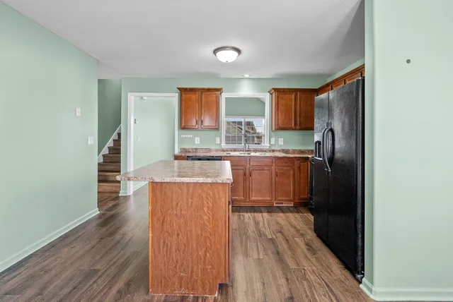 a kitchen with kitchen island wooden floors granite counter tops and a window