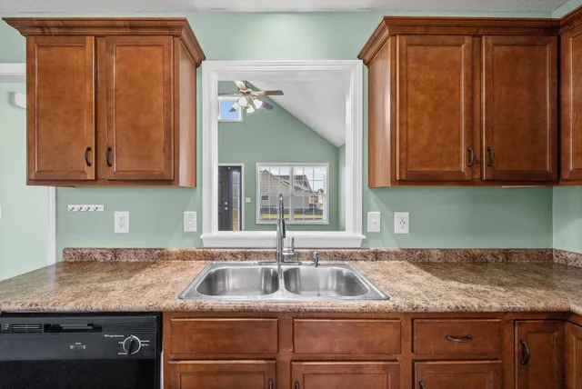 a kitchen with granite countertop a sink and dishwasher cabinets with wooden floor