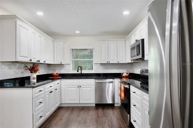 a kitchen with stainless steel appliances granite countertop white cabinets sink and stove
