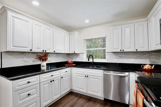 a kitchen with white cabinets and sink
