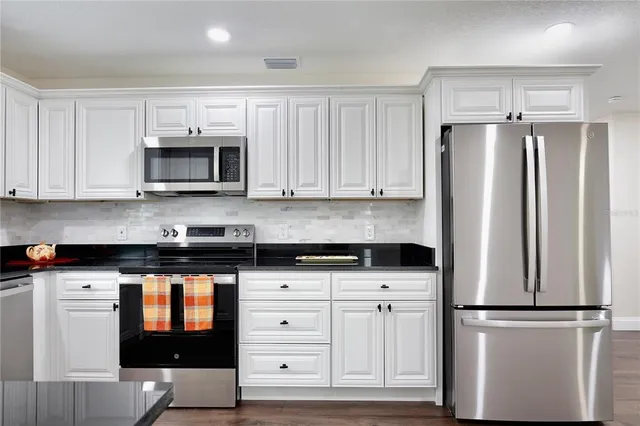 a kitchen with white cabinets and stainless steel appliances