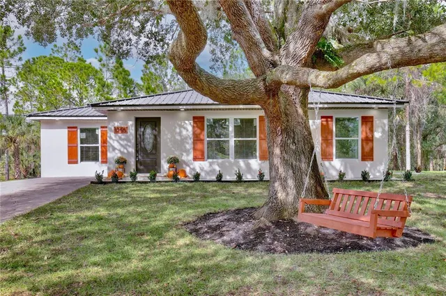 a view of a house with backyard and a tree