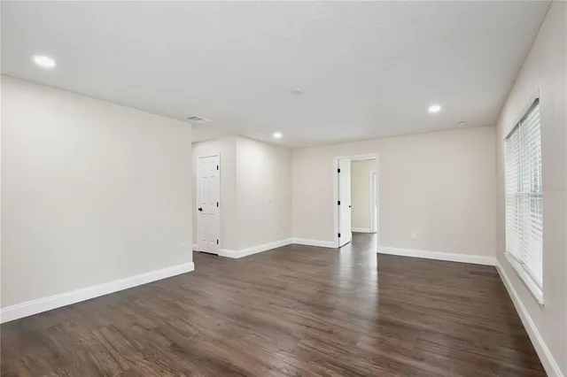 a view of an empty room with wooden floor and window