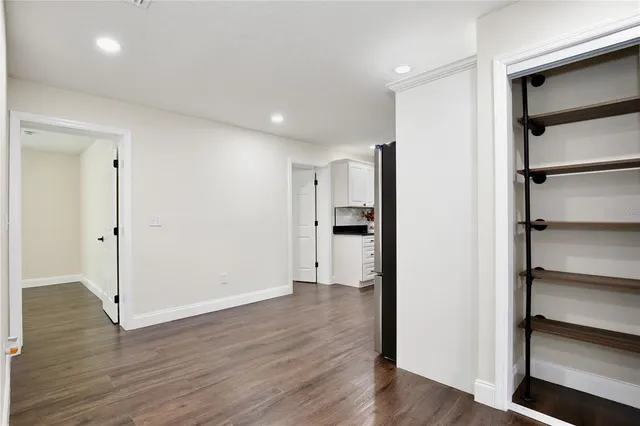 a view of an empty room with wooden floor and closet