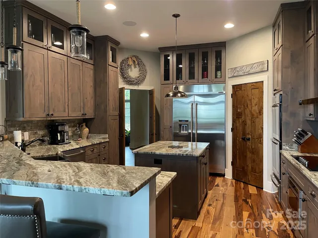 a kitchen with stainless steel appliances kitchen island granite countertop a refrigerator and a sink