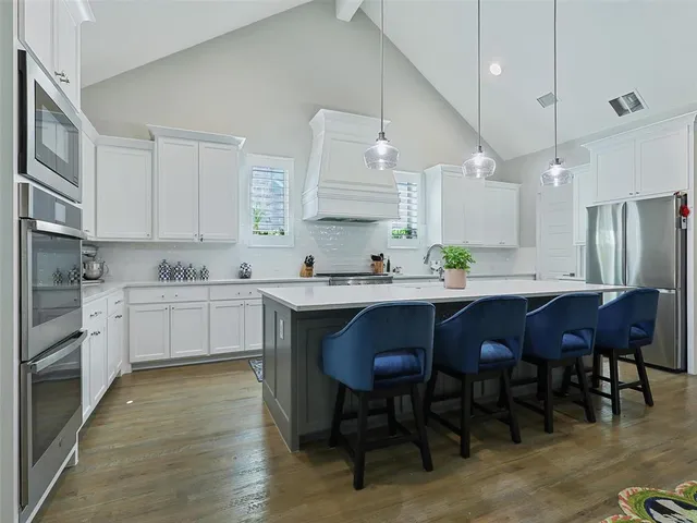 a kitchen with stainless steel appliances granite countertop a table chairs sink refrigerator and cabinets