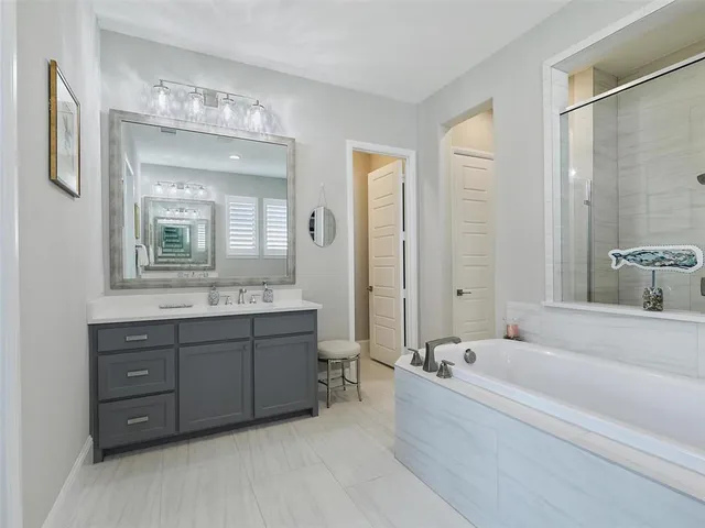 a spacious bathroom with a tub sink shower and mirror