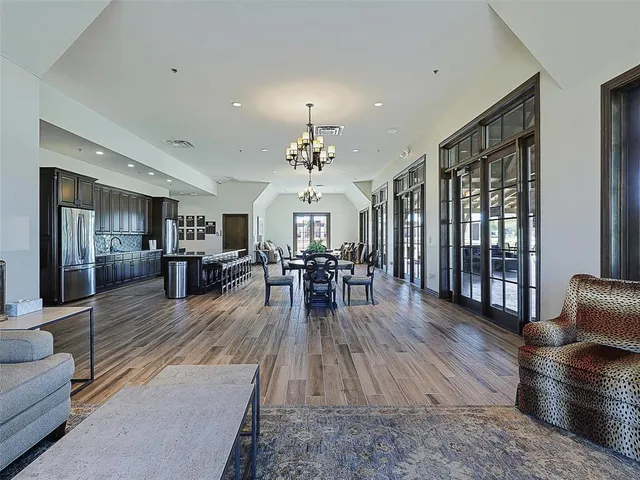 a living room with furniture dining table a wooden floor and a large window