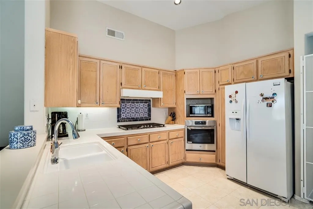 7570 Windy Ridge Road San Diego, CA 92126 - Photo 13 of 25 a kitchen with stainless steel appliances a refrigerator sink and cabinets