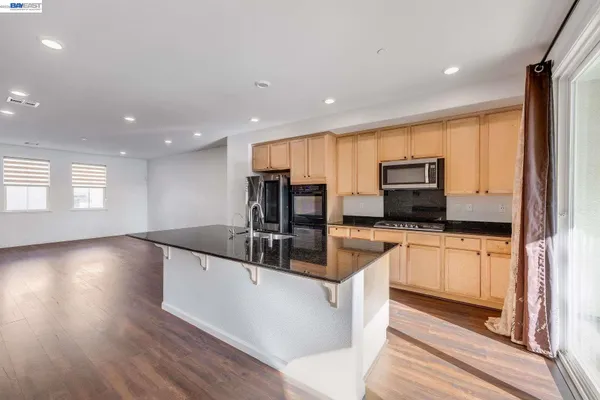 a large kitchen with stainless steel appliances a large counter top a stove a sink and a refrigerator