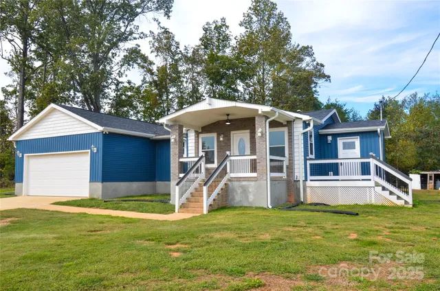 a view of a house with a yard potted plants and a large tree