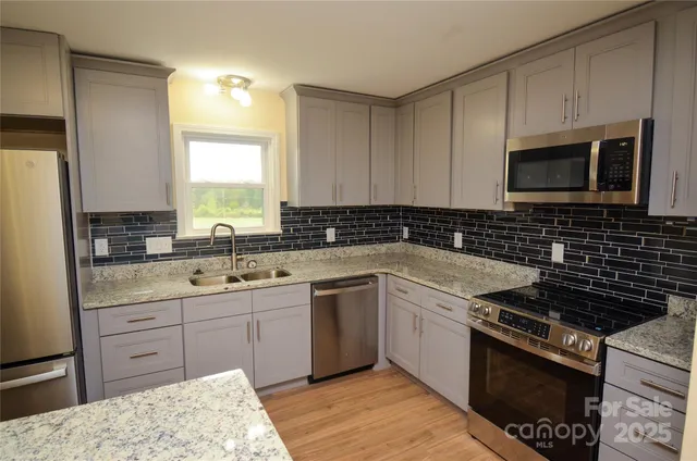 a kitchen with cabinets appliances a sink and a window