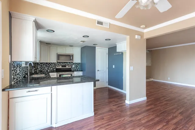 a large kitchen with stainless steel appliances kitchen island a large counter top and wooden floors