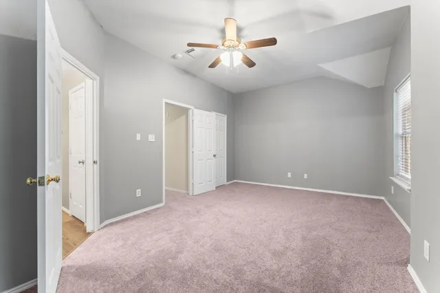an empty room with ceiling fan and window