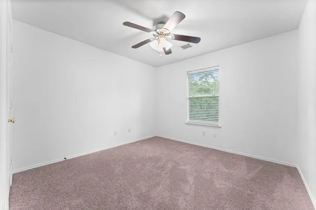 an empty room with ceiling fan and window
