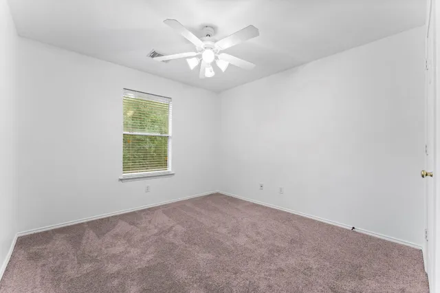 an empty room with windows and chandelier fan