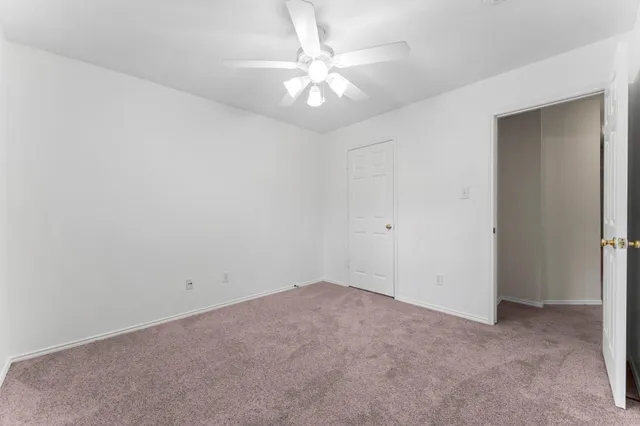 an empty room with a chandelier fan and windows