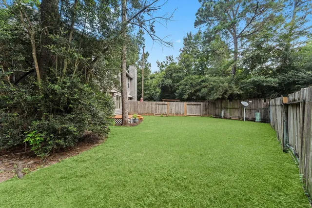 a view of a backyard with large trees and wooden fence