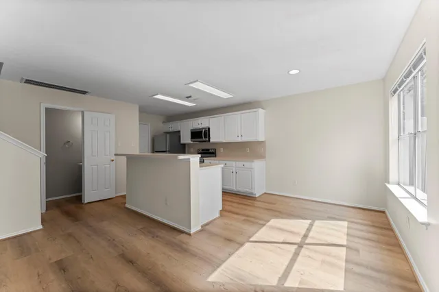 a view of a kitchen with white cabinets and wooden floor