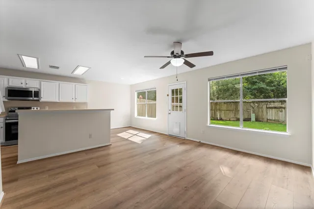 a view of an empty room with a window and wooden floor