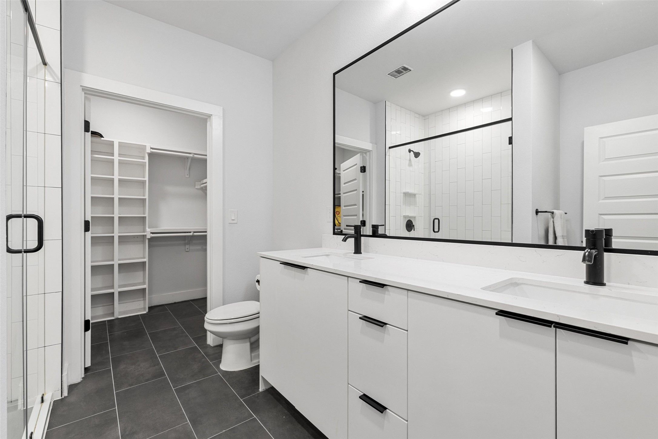 2500 Longview Street, Unit 418 Austin, TX 78705 - Photo 17 of 40 Full bathroom with a walk in closet, double vanity, a stall shower, and dark tile patterned flooring