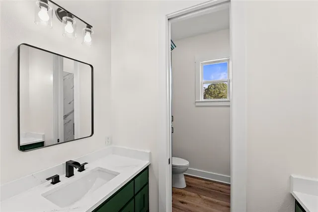 a bathroom with a sink vanity granite toilet and a mirror