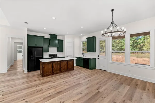 a large kitchen with stainless steel appliances granite countertop a large window a oven and a wooden floors
