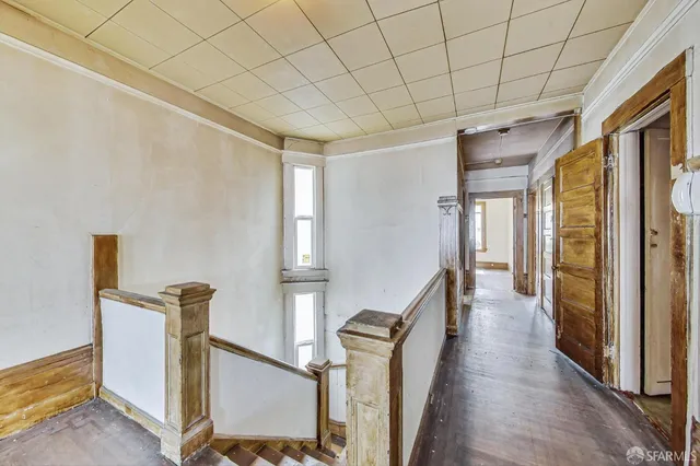 a view of a hallway with wooden floor and staircase