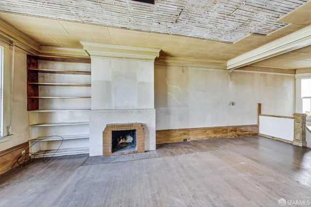 a view of an empty room with a fireplace and a window