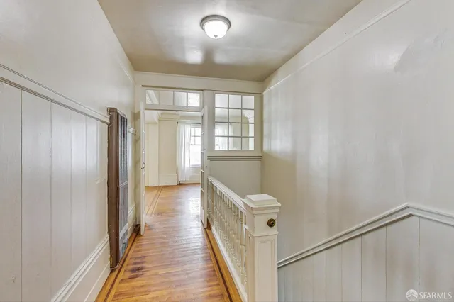 a view of a hallway with wooden floor and staircase