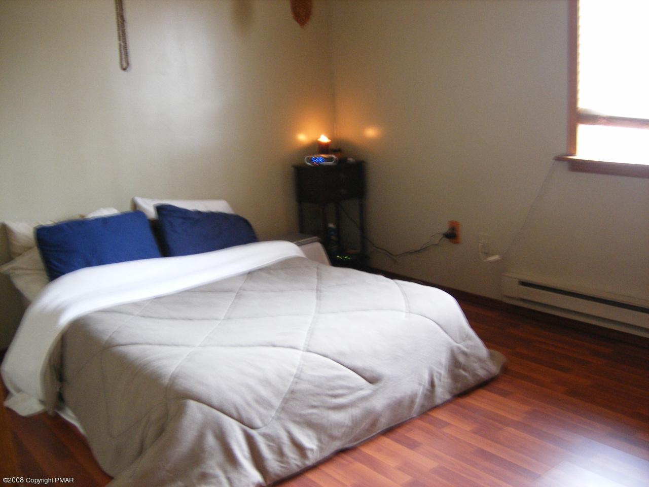 112 Bromley Road Henryville, PA 18332 - Photo 10 of 13 a bedroom with a bed and a lamp with wooden floor