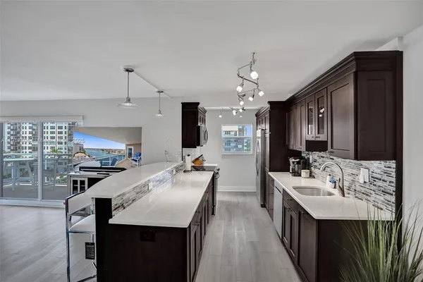 a large kitchen with a sink a counter space and stainless steel appliances