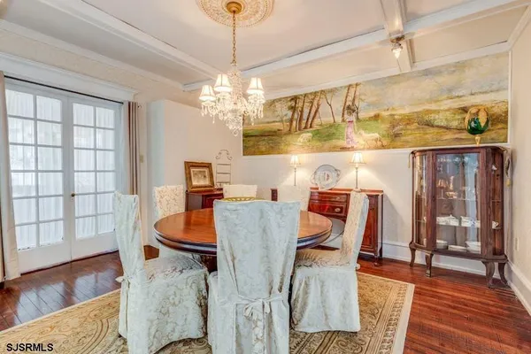 a dining room with wooden floor a chandelier a glass table and chairs