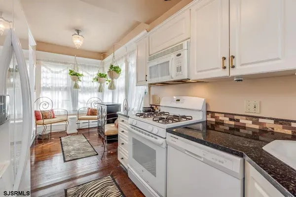 a kitchen with stainless steel appliances granite countertop a stove and white cabinets