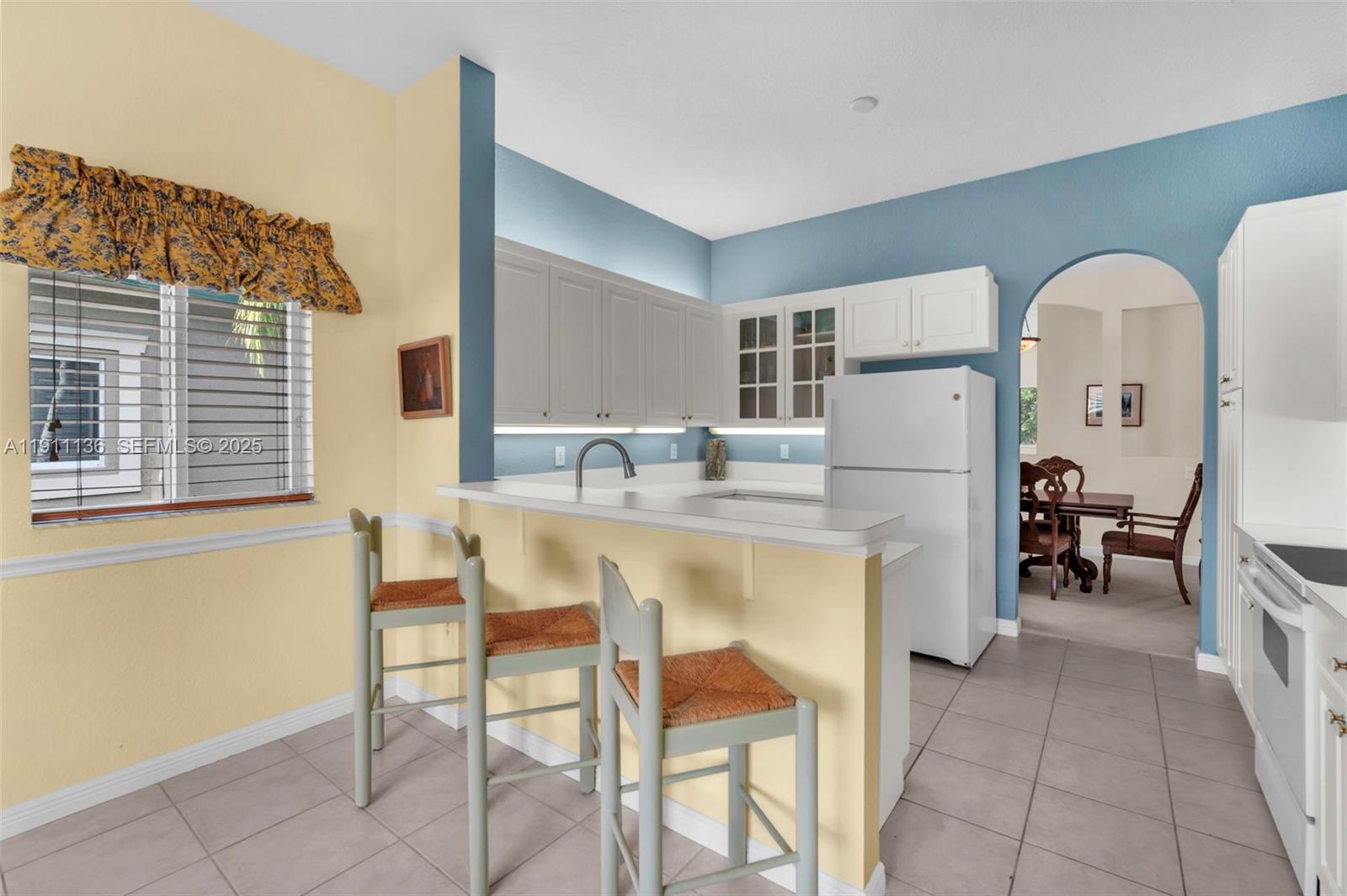 7921 Exeter Boulevard East, Unit 202 Tamarac, FL 33321 - Photo 13 of 55 a dining room with kitchen island stainless steel appliances a table and chairs in it