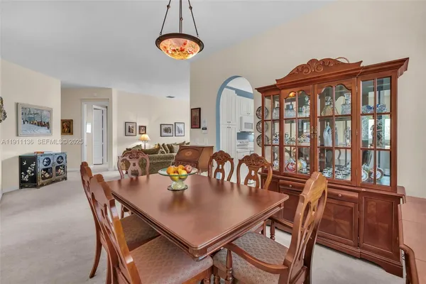 a view of a dining room and livingroom with furniture wooden floor a rug a fireplace and a chandelier