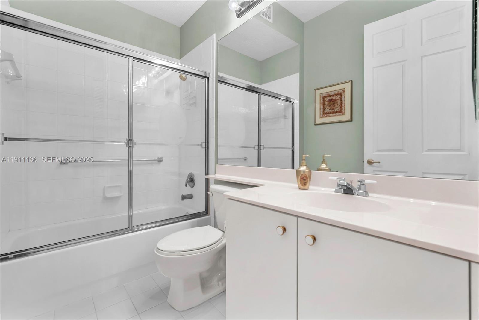 7921 Exeter Boulevard East, Unit 202 Tamarac, FL 33321 - Photo 29 of 55 a bathroom with a granite countertop sink a toilet and shower